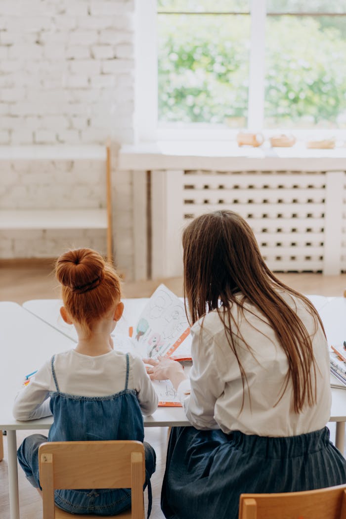 contact-img A mother and her daughter sitting at a table, engaged in learning activities inside a bright room.