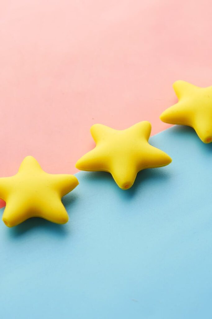 Yellow stars on pink and blue pastel background for rating or review concept.